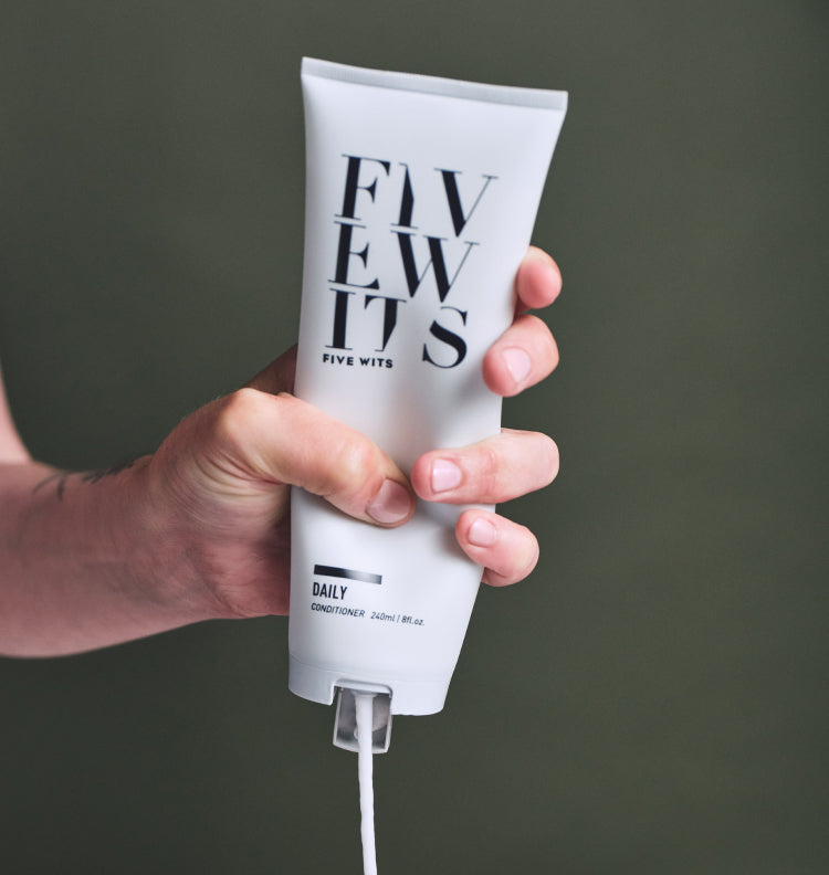 hand squeezing Five Wits daily conditioner bottle