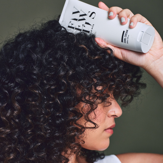 woman with curly hair holding Five Wits curl cream product