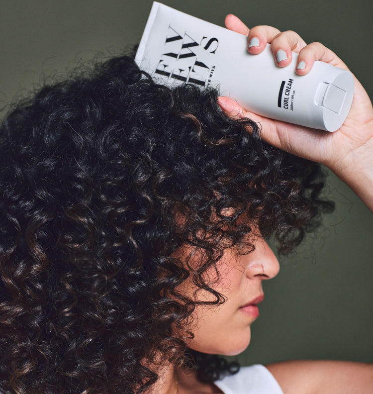 curly hair woman holding Five Wits curl cream bottle