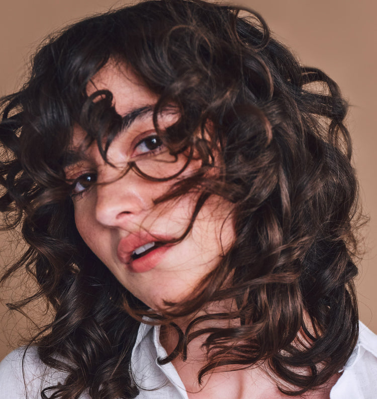 young woman flipping long wavy hair over face